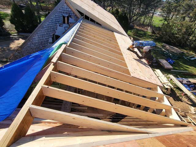 New roof framing next to a tarped roof