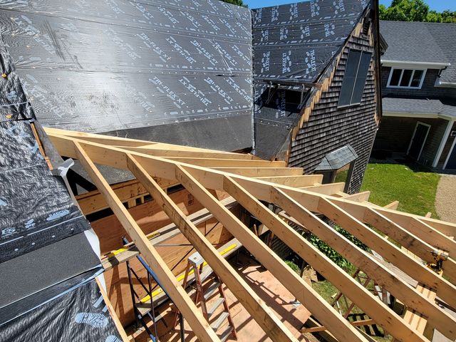 Roof framing next to an asphalt shingle roof