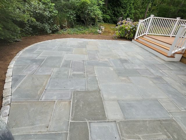 Curved bluestone patio next to a deck
