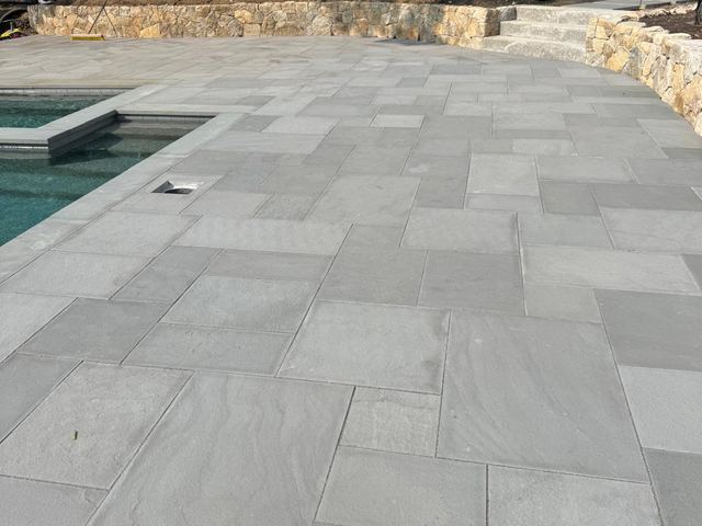 Bluestone patio around an in-ground pool with stone walls behind