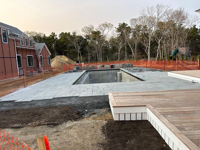 Bluestone pool surround next to a wood deck during construction