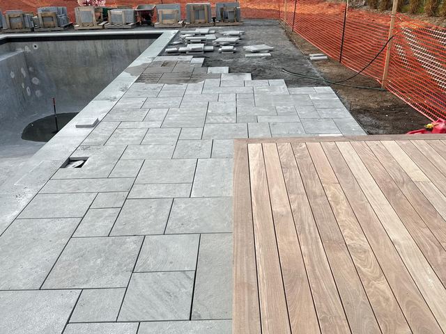 Bluestone pool patio being laid beside a wood deck