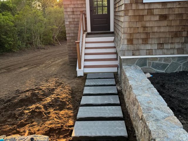 Bluestone steps and walk beside a stone wall at a side entry