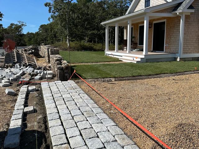 Granite cobblestone walkway being laid toward a house