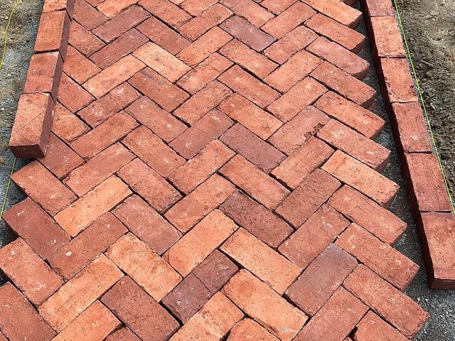 Red brick walkway laid in a herringbone pattern with a soldier course border