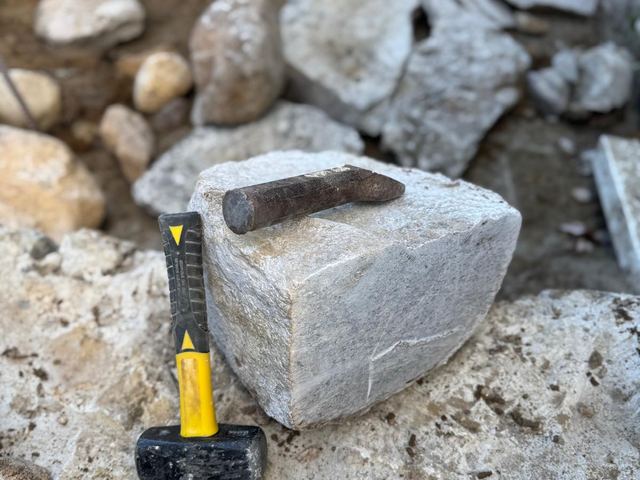 Shaping a stone block by hand with a hammer