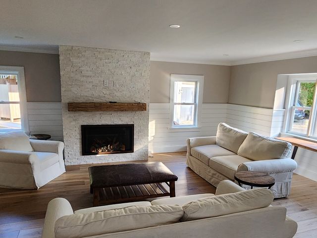 Living room with stone fireplace, shiplap walls and wide-plank floors