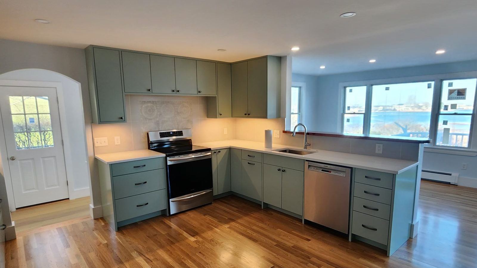 Kitchen with custom green cabinets and hardwood floors